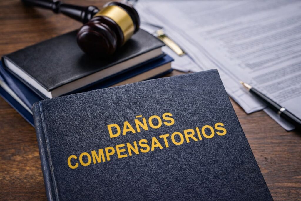 Daños compensatorios en casos de lesiones personales en Texas Libro legal con el texto “Daños compensatorios” junto a un mazo de juez y documentos, representando compensación legal por lesiones personales