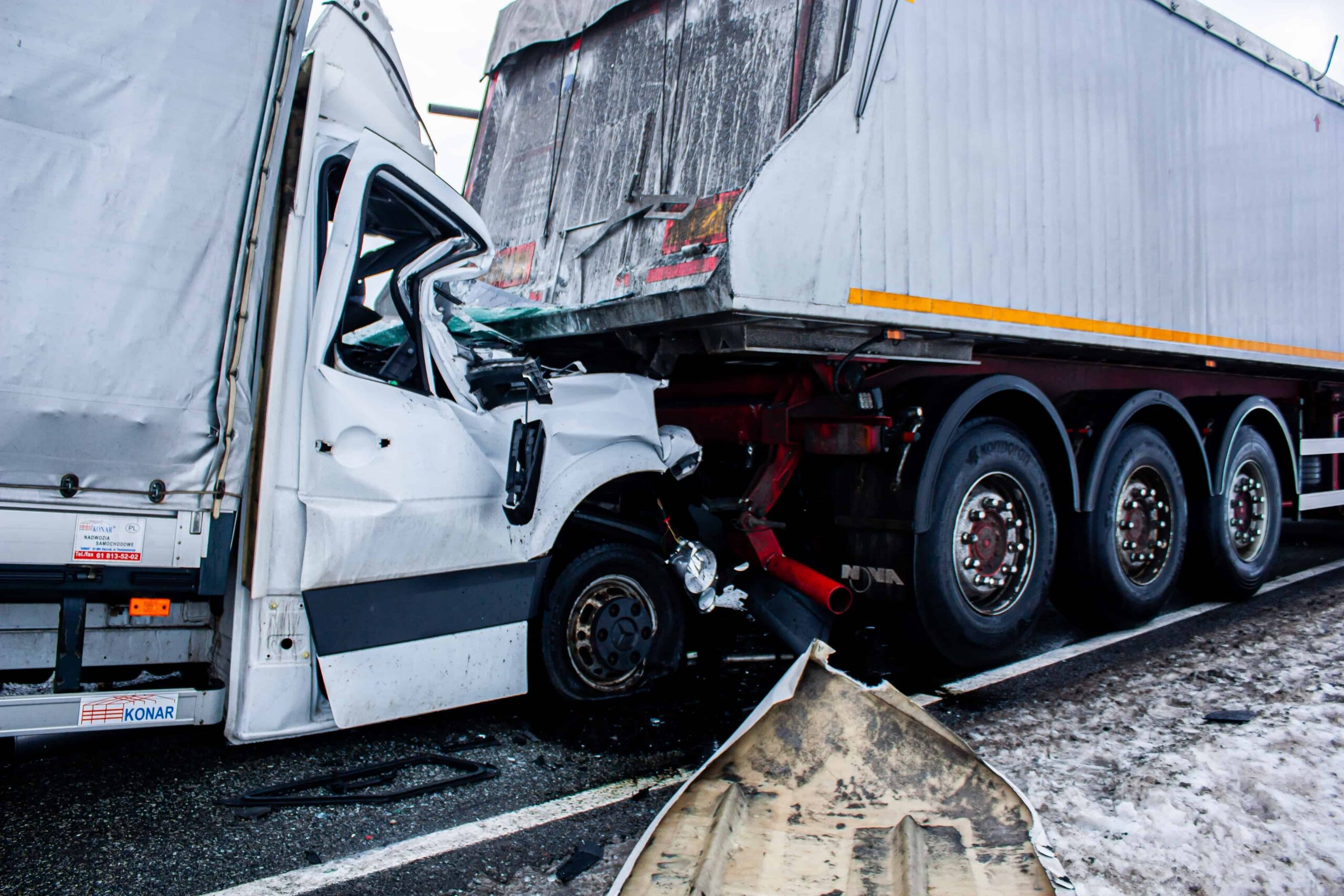 Severe semi-truck collision with crushed cab under trailer, depicting a serious highway accident and commercial truck crash scene