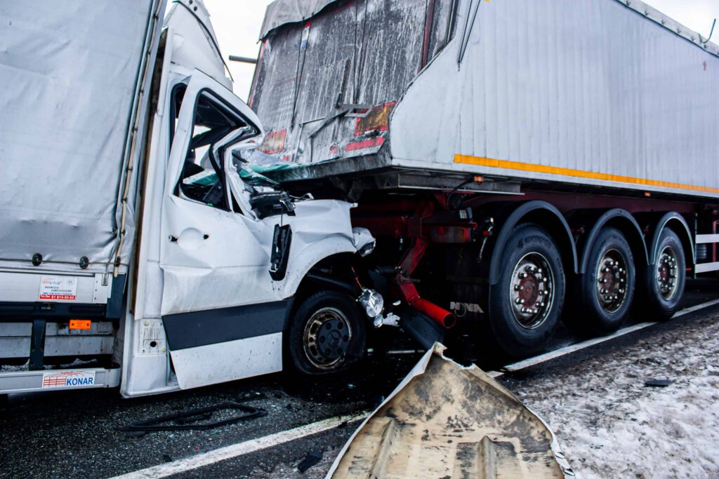 Severe semi-truck collision with crushed cab under trailer, depicting a serious highway accident and commercial truck crash scene Severe semi-truck collision with crushed cab under trailer, depicting a serious highway accident and commercial truck crash scene