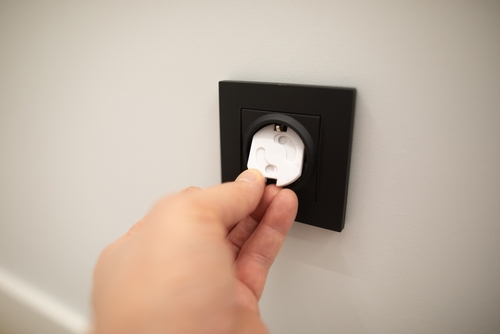 Hand plugging into a wall outlet, highlighting electrical hazard risks handled by a Houston electrocution accident lawyer.