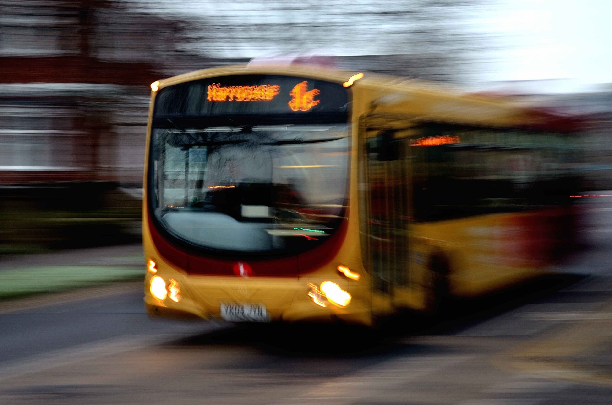 Blurred city bus in motion on urban street, representing public transportation speed, traffic conditions, and bus accident risk