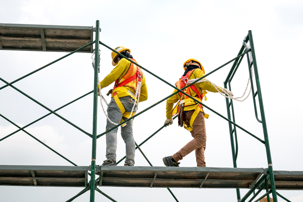 Construction workers safely tethered to scaffolding