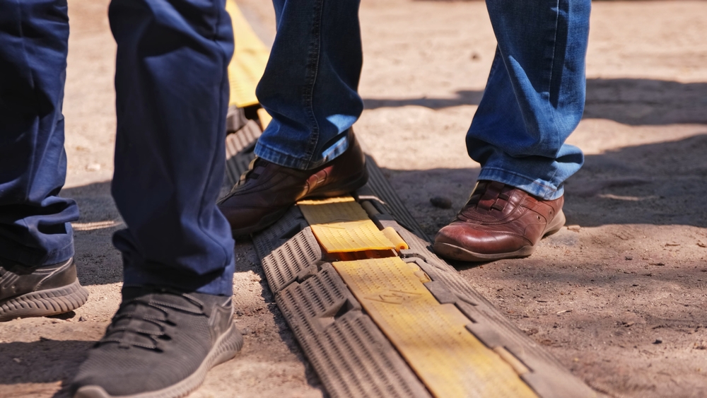 Construction workers stepping over ground cover for electric cables